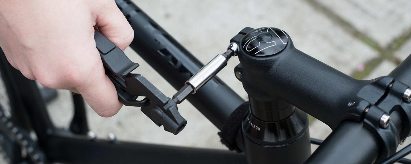 A hand holding an Allen key tool, fixing a bike