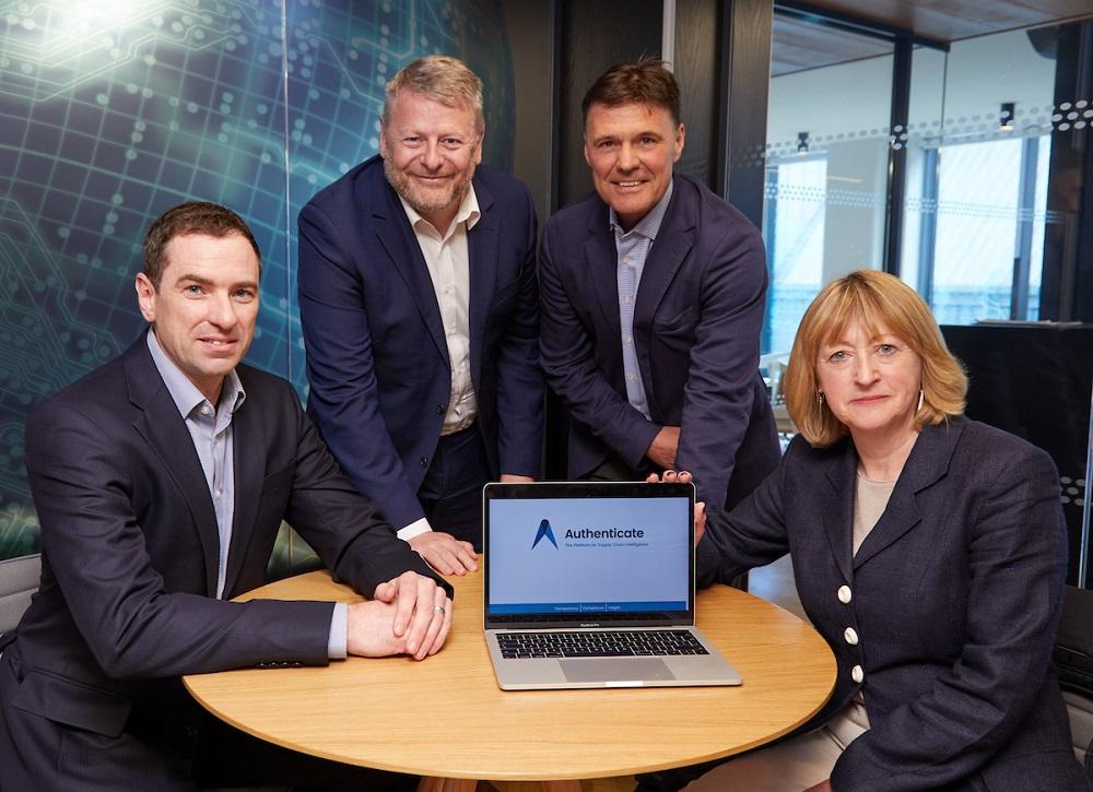 3 men and a woman gathered around a table with a laptop displaying the Authenticate web page