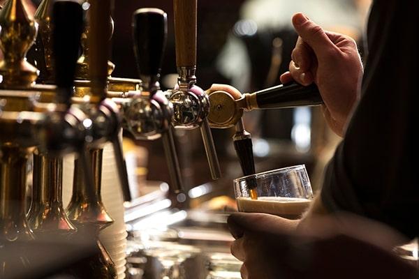 Closeup of a bartender pouring a dark stout beer in tap