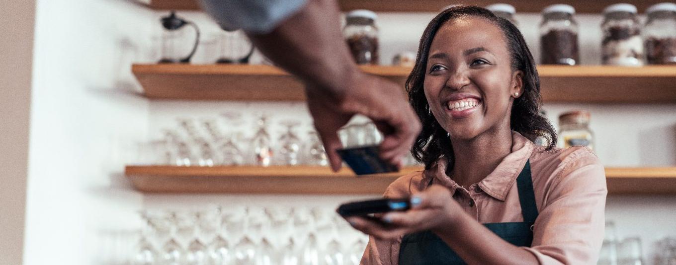 Customer paying for a coffee by tapping credit card on payment machine
