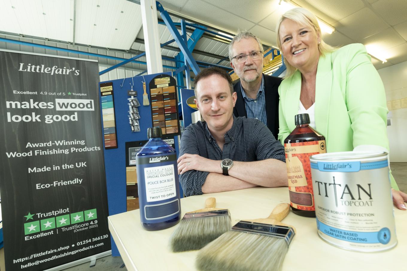 people standing with a display of paint tins and paint brushes on a table