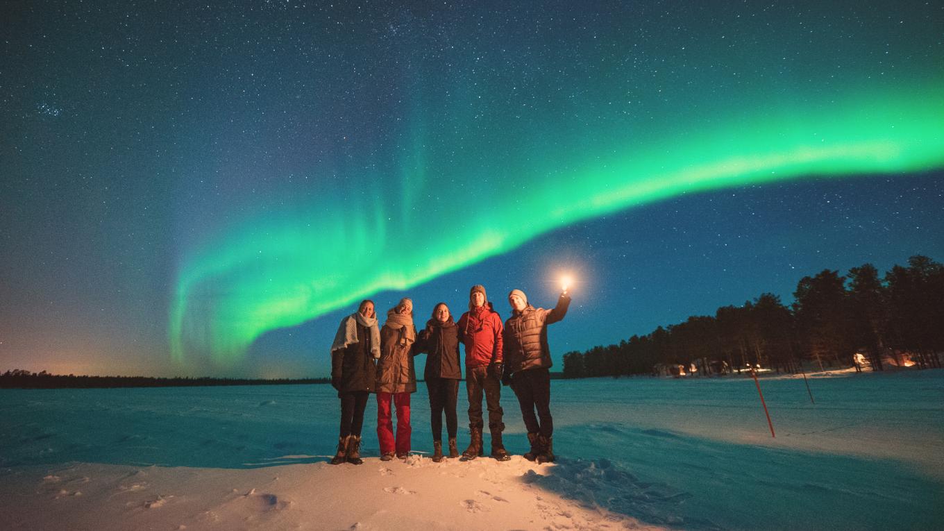 Four people standing in front of the northern lights 