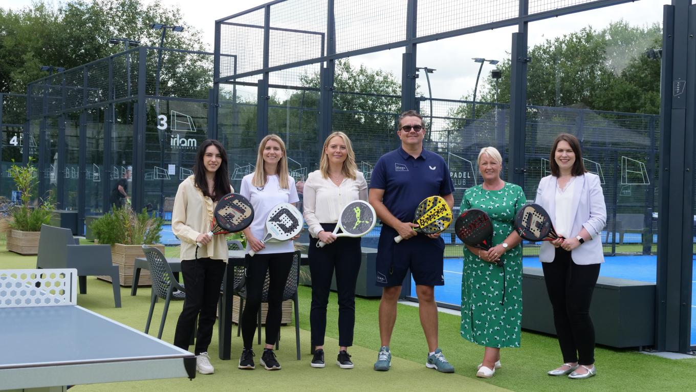 a group of people standing with pedal rackets in a court