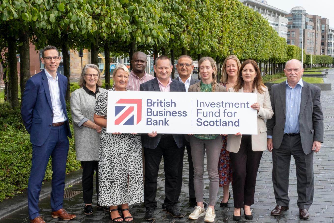 Photo of British Business Bank, Maven, The FSE Group and DSL members of staff outside in Glasgow holding an Investment Fund for Scotland logo printed on a big sign