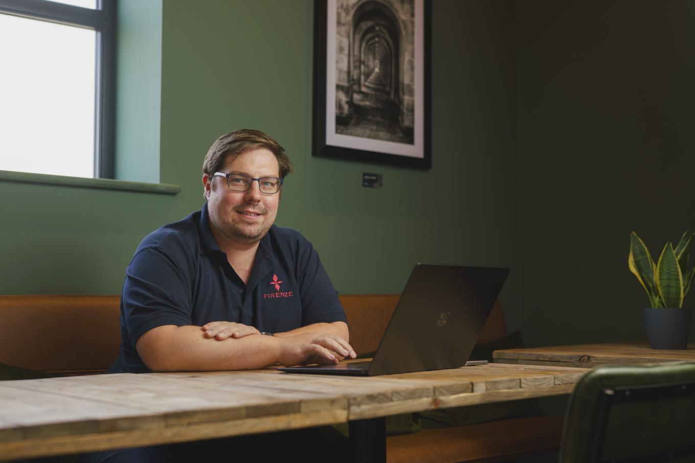 Firenze CEO David, sat at a table with an open laptop