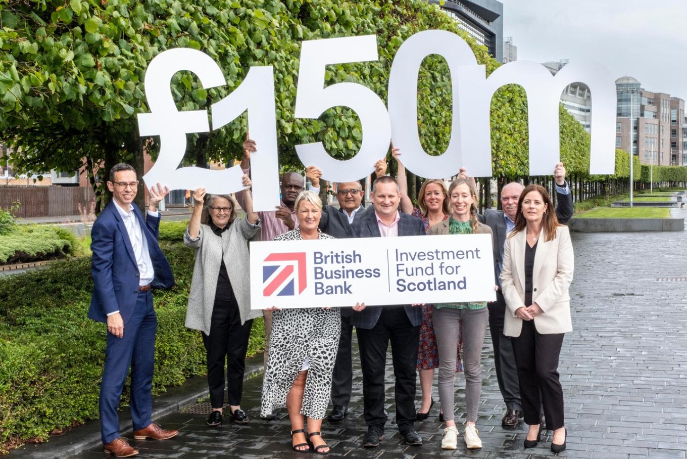 A mixed group of people celebrating by holding a £150m sign and the IFS logo
