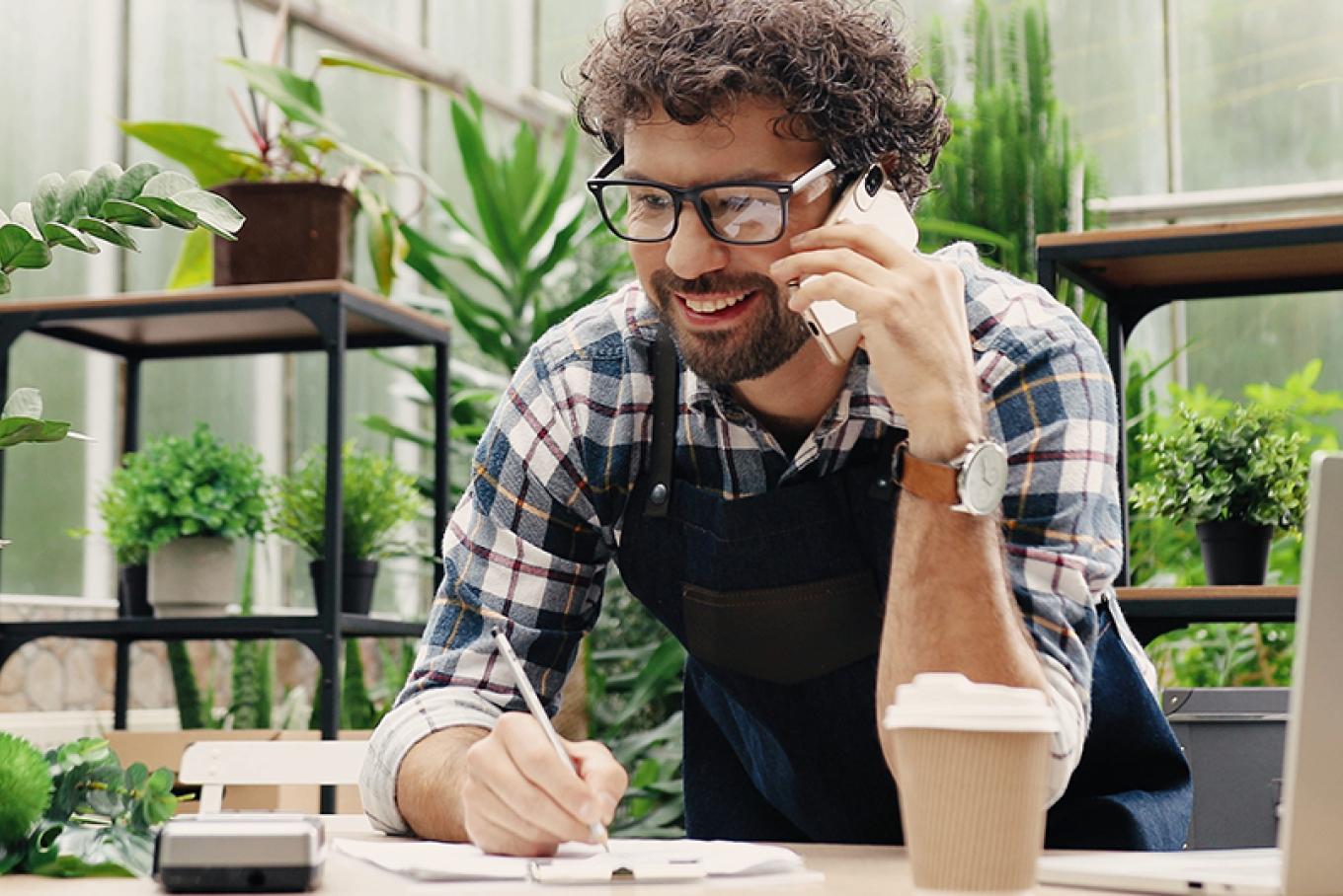 A businessman in a greenhouse style environment on the telephone